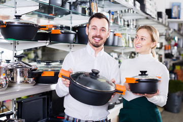 Man and woman demonstrate saucepans