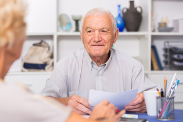 Smiling senior man discussing with wife bills