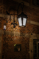 Wand us rotem Backstein in einer dunklen Gasse mit alter Laterne