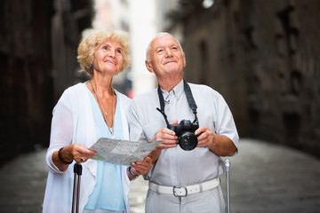 Senior man photographing sights while his wife looking map near old cathedral