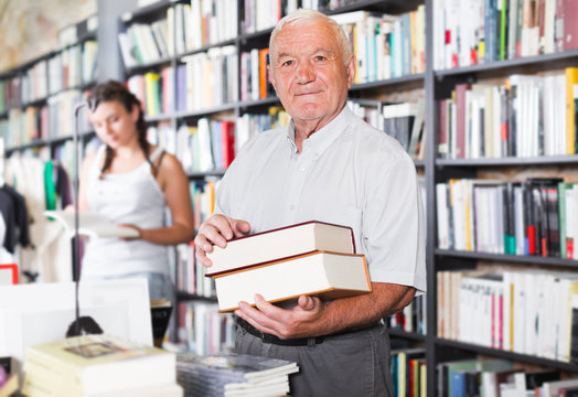 Portrait of mature man cutomer is demonstrating books