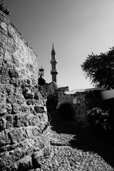Alter Burgmauern mit Olivenbaum und Minarett im Hintergrund
