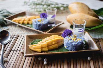 Thai dessert - Mango with butterfly pea sticky rice and coconut sauce serve on banana leaf