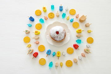 Image of jewish holiday Hanukkah with wooden dreidels colection (spinning top) and doughnut over white background.