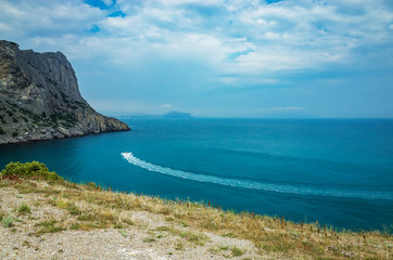 Fototapeta na wymiar Boat in the bay among the mountain range, Sudak district, Crimea