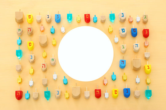 Image of jewish holiday Hanukkah with wooden dreidels colection (spinning top) over pastel yellow background.