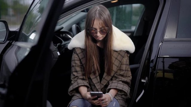 Young woman using smartphone in car