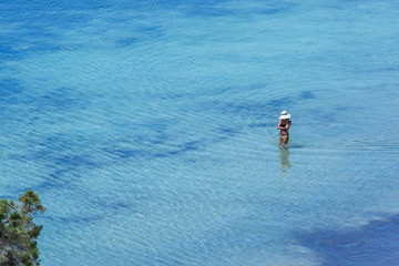 Woman walking on beach shore with turquoise water