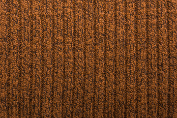 Texture of a brown knitted sweater closeup. orange knitted wool material background