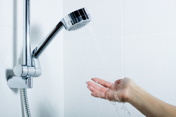the hand of the girl reaches for the silver shower which stands in the holder. splashing