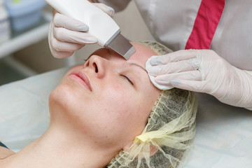 Cosmetologist doing procedure cleaning of face with ultrasonic scrubber