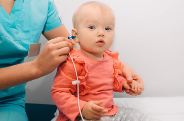 doctor check a baby girl's ears. Little baby having hearing test , procedure impedance audiometry