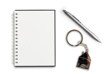 Schreibblock, Stift und Schlüsselanhänger in Hausform auf weißem Hintergrund