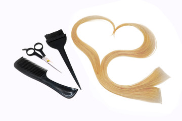 a strand of blond hair in the shape of a heart, brushes, scissors and comb , hairdressing tools on a white background, isolated