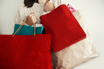Christmas Shopping and seasonal sale. Happy Girl in sweater holding red and green paper shopping Bags. Shopping Center. Christmas Sales. Space for text.  Black Friday.