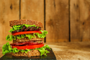 Sandwiches - bread, meat, basil, fresh leaves of lettuce on a wooden background. top view. copy space