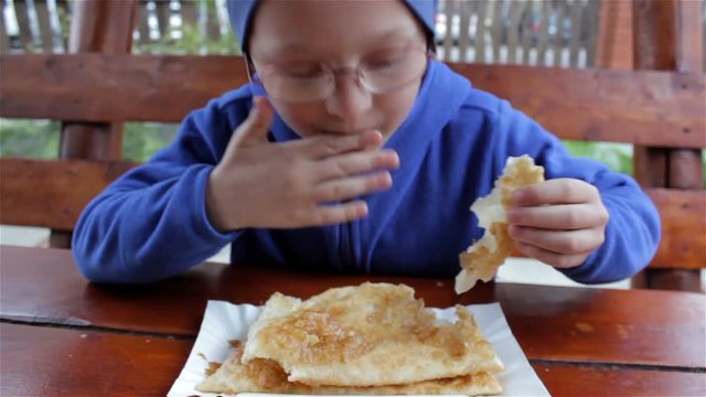 boy eats hot chebureki,boy in glasses for sight eats chebureki