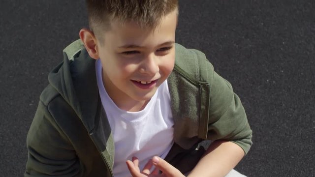 Close-up view of smiling little boy sitting on legs of father and counting reps of sit ups during outdoor workout on playground