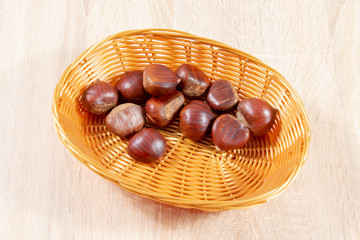 Obraz premium chestnuts in basket on wooden background