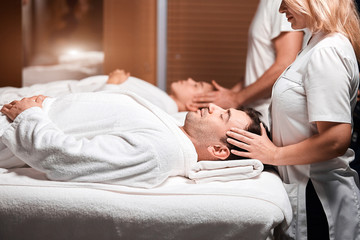 Beautiful young male and female tourists lying on massage table with closed eyes, totaly relaxed...
