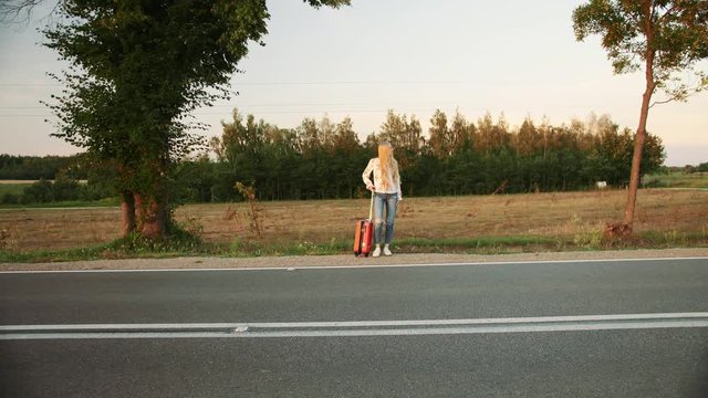 Young woman hitchhiking on countryside road.