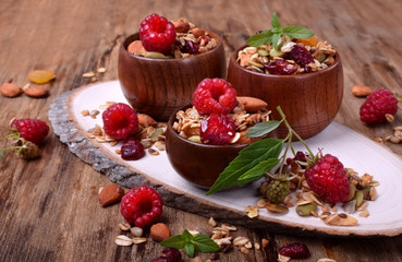 Granola decorated with raspberries in wooden bowls on the table