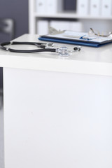 Stethoscope and medical history form lying at reception desk. Medical tools at doctor working table in clinic or emergency hospital. Medicine and healthcare concept