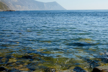 The black sea with blue water on a clear sunny day and mountains with forests are ideal for relaxing. The sun, the mountains and the sea is a great concept of nature for design.