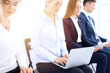Fototapeta premium Group of business people sitting in office waiting for job interview, close-up. Hands of woman working on laptop. Conference or training concepts
