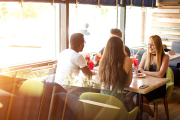 Hungry multiethnic male and female co-workers having lunch break together eating pizza in corporative diner, discussing working projects.