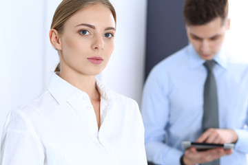 Obraz premium Beautiful blonde businesswoman using tablet pc while standing straight in a brightly lit office. Business concept