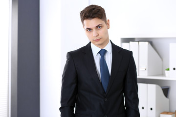 Young businessman standing straight in office. Business concept