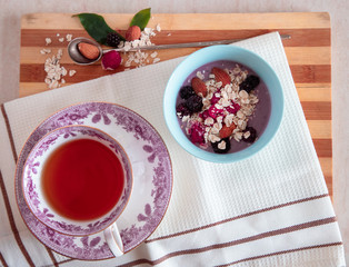 A cup of tea  with granola and fresh fruits