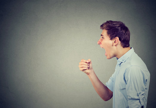 Screaming young man on gray background