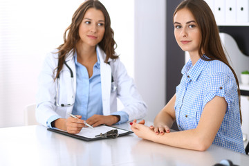Doctor and  happy patient  talking while sitting at the desk. The physician or therapist discussing healthy lifestyle. Health care, medicine and patient service concept