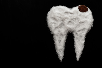 tooth made of sugar on a black background with caries