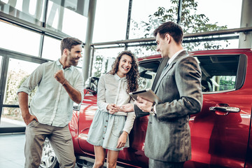Couple receiving car keys by a dealer in a dealership