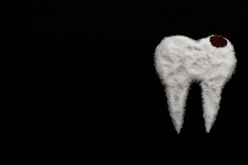 tooth made of sugar on a black background with caries