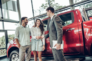 Salesman in car dealership giving keys to clients