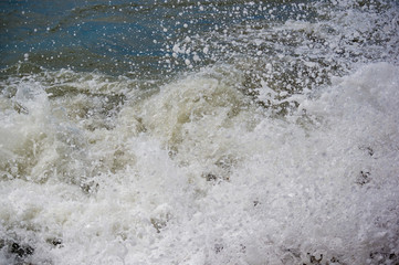 pebble stones on the sea beach, the rolling waves of the sea with foam