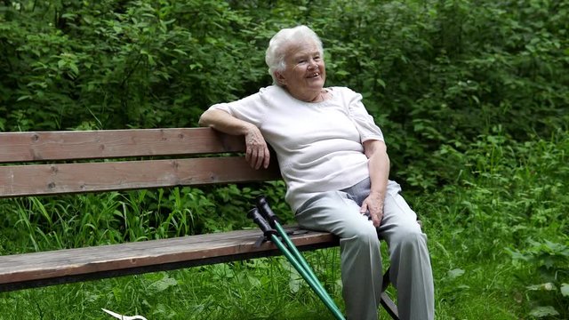 old granny sits resting on a park bench
