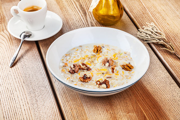 Oatmeal porridge bowl with nuts, pumpkin and honey. Healthy nutritious breakfast with cup of coffee. Copy space for text, brand or logo. Recipe and idea healthy vegan breakfast. Breakfest concept.