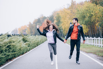 Romantic holidays guy and girls in autumn park.
Funny games of husband and wife in nature.