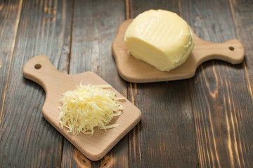 Grated cheese for cooking on a wooden background.