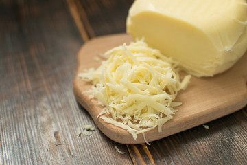 Grated cheese for cooking on a wooden background.