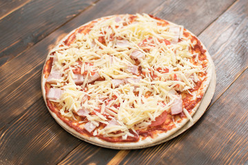 Raw pizza on wooden background.
