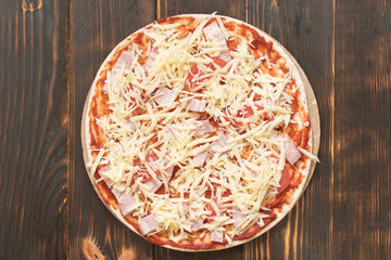 Raw pizza on wooden background.