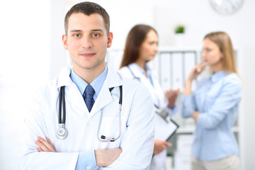 Friendly male doctor  on the background with patient  and physician