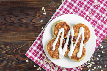 Oat cottage cheese pancakes, syrniki, curd fritters with strawberry jam in a white plate. Gourmet Breakfast.