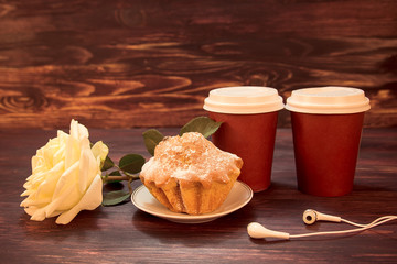 Cups of coffee, a cupcake and headphones on blue background